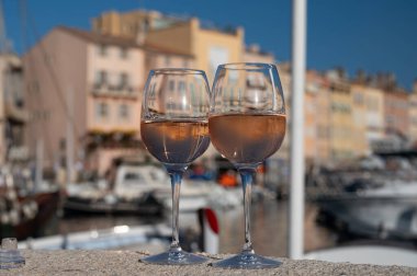 Saint-Tropez 'de eski balıkçı tekneleri limanı ve yat limanında soğuk Fransız gülü Cote de Provence şarabı, Fransa' nın Provence şehrinde yaz tatili