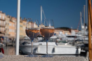 Saint-Tropez 'de eski balıkçı tekneleri limanı ve yat limanında soğuk Fransız gülü Cote de Provence şarabı, Fransa' nın Provence şehrinde yaz tatili