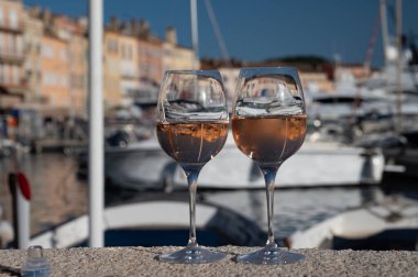 Saint-Tropez 'de eski balıkçı tekneleri limanı ve yat limanında soğuk Fransız gülü Cote de Provence şarabı, Fransa' nın Provence şehrinde yaz tatili
