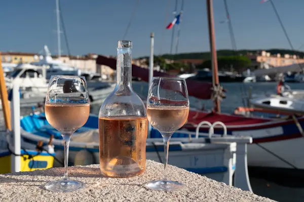 Saint-Tropez 'de eski balıkçı tekneleri limanı ve yat limanında soğuk Fransız gülü Cote de Provence şarabı, Fransa' nın Provence şehrinde yaz tatili