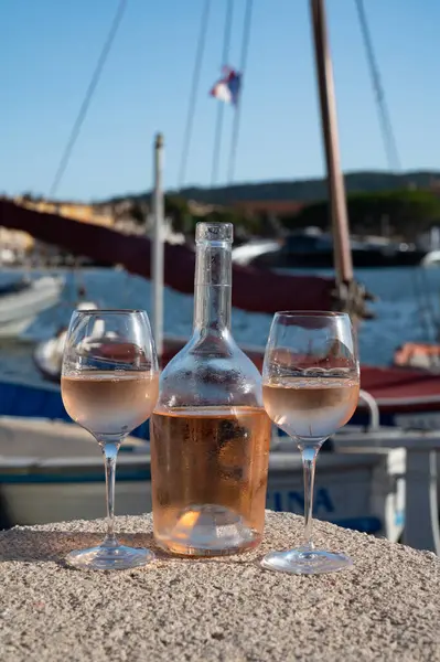 Saint-Tropez 'de eski balıkçı tekneleri limanı ve yat limanında soğuk Fransız gülü Cote de Provence şarabı, Fransa' nın Provence şehrinde yaz tatili