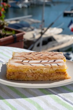 Portion of french mille-feuille cake, vanilla or custard slice, Napoleon puff pastry layered with pastry cream served outdoor in Port Grimaud, France clipart