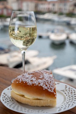 Fransız Rivierası 'nın şarap ve kekleri, bir bardak soğuk beyaz Cote de Provence şarabı ve Port Grimaud limanında Tarte Tropezienne keki, Fransa' nın Provence şehrinde yaz tatili