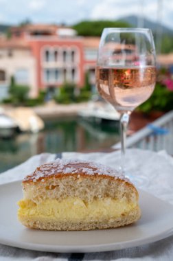 Fransız Riviera şarabı, bir bardak soğuk gül Cote de Provence şarabı ve Port Grimaud 'un yat limanında Tarte Tropezienne keki, Fransa' nın Provence şehrinde yaz tatili