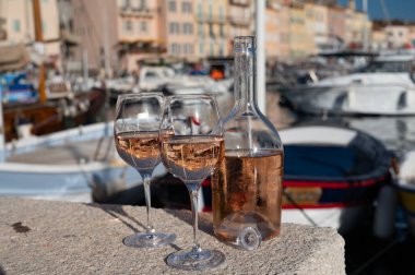 Saint-Tropez 'de eski balıkçı tekneleri limanı ve yat limanında soğuk Fransız gülü Cote de Provence şarabı, Fransa' nın Provence şehrinde yaz tatili