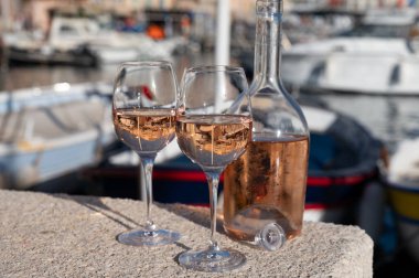Saint-Tropez 'de eski balıkçı tekneleri limanı ve yat limanında soğuk Fransız gülü Cote de Provence şarabı, Fransa' nın Provence şehrinde yaz tatili