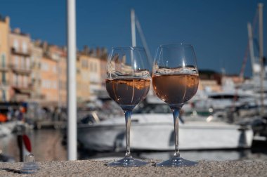 Saint-Tropez 'de eski balıkçı tekneleri limanı ve yat limanında soğuk Fransız gülü Cote de Provence şarabı, Fransa' nın Provence şehrinde yaz tatili