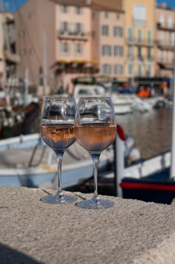 Saint-Tropez 'de eski balıkçı tekneleri limanı ve yat limanında soğuk Fransız gülü Cote de Provence şarabı, Fransa' nın Provence şehrinde yaz tatili