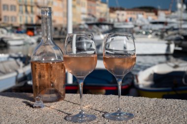 Saint-Tropez 'de eski balıkçı tekneleri limanı ve yat limanında soğuk Fransız gülü Cote de Provence şarabı, Fransa' nın Provence şehrinde yaz tatili