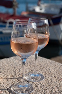 Glasses of cold french rose Cote de Provence wine in old fisherman boats port and yachts harbour in Saint-Tropez, summer vacation on French Riviera in Provence, France clipart