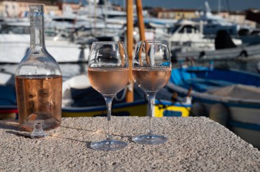 Saint-Tropez 'de eski balıkçı tekneleri limanı ve yat limanında soğuk Fransız gülü Cote de Provence şarabı, Fransa' nın Provence şehrinde yaz tatili