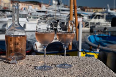 Saint-Tropez 'de eski balıkçı tekneleri limanı ve yat limanında soğuk Fransız gülü Cote de Provence şarabı, Fransa' nın Provence şehrinde yaz tatili