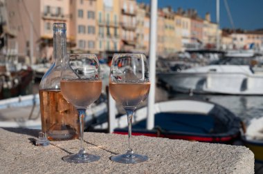 Saint-Tropez 'de eski balıkçı tekneleri limanı ve yat limanında soğuk Fransız gülü Cote de Provence şarabı, Fransa' nın Provence şehrinde yaz tatili