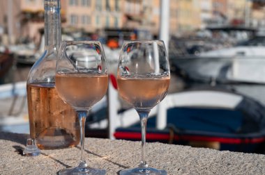 Saint-Tropez 'de eski balıkçı tekneleri limanı ve yat limanında soğuk Fransız gülü Cote de Provence şarabı, Fransa' nın Provence şehrinde yaz tatili