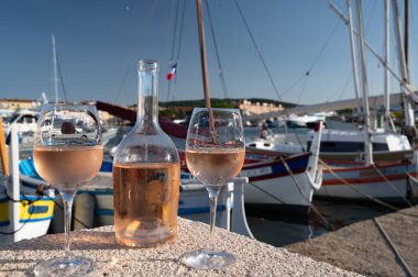 Saint-Tropez 'de eski balıkçı tekneleri limanı ve yat limanında soğuk Fransız gülü Cote de Provence şarabı, Fransa' nın Provence şehrinde yaz tatili