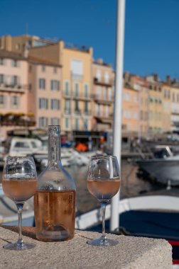 Saint-Tropez 'de eski balıkçı tekneleri limanı ve yat limanında soğuk Fransız gülü Cote de Provence şarabı, Fransa' nın Provence şehrinde yaz tatili