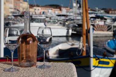 Saint-Tropez 'de eski balıkçı tekneleri limanı ve yat limanında soğuk Fransız gülü Cote de Provence şarabı, Fransa' nın Provence şehrinde yaz tatili