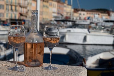 Saint-Tropez 'de eski balıkçı tekneleri limanı ve yat limanında soğuk Fransız gülü Cote de Provence şarabı, Fransa' nın Provence şehrinde yaz tatili