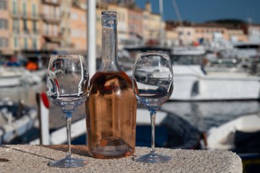 Saint-Tropez 'de eski balıkçı tekneleri limanı ve yat limanında soğuk Fransız gülü Cote de Provence şarabı, Fransa' nın Provence şehrinde yaz tatili