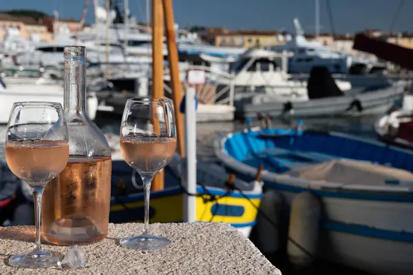 Saint-Tropez 'de eski balıkçı tekneleri limanı ve yat limanında soğuk Fransız gülü Cote de Provence şarabı, Fransa' nın Provence şehrinde yaz tatili