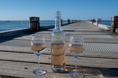 Provence 'den getirilen soğuk gül şarabı, mavi deniz manzaralı ahşap yat rıhtımında ve Saint-Tropez yakınlarındaki plaj plajında sergileniyordu.