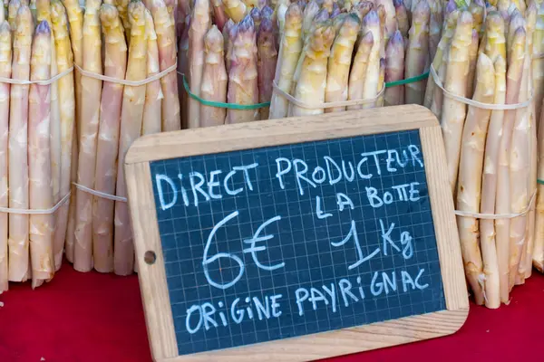 Souillac, Dordogne, Fransa 'daki yerel çiftçi pazarında satılık taze çiğ, pembe kuşkonmaz sebzeleri. İngilizce çeviri: Payrignac 'ta yerel üretilen 1 kg deste