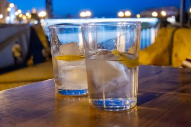 Glasses of cold mineral sparkling water served outdoor with ice cubes in cafe at night in historical Triana district, Sevilla, Spain, close up clipart