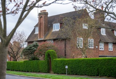 Kuzey Londra sokaklarında yürümek, baharda kırmızı tuğlalı evler ve çiçek açan bahçeler, şehir hayatı, Mart ayında Londra, İngiltere 'de zengin mahalleler.