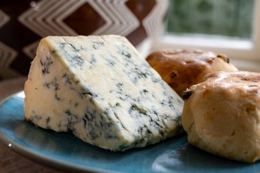 Cheese collection, English cow milk semi-soft, crumbly old stilton blue cheese and baked scones buns close up clipart