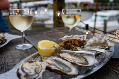 Güneşli bir günde, Arcachon Bassin, Gujan-Mestras limanı, Bordeaux, Fransa 'da, istiridye sayısı 0 olan istiridye çiftçilik köyündeki açık hava kafesinde taze canlı istiridye ve ekmek yemek..