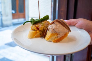 Typical snacks of Basque Country, pinchos or pinxtos skewers with small pieces of bread, fish, sea food, sweet green pepper served in bar in San-Sebastian or Bilbao, Spain, close up clipart