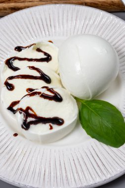 Tasty italian food, fresh white buffalo milk mozzarella soft cheese balls served with balsamic vinegar from Modena from Campania close up clipart