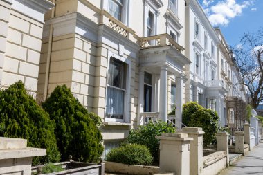 Notting Hill, baharda beyaz evler ve çiçek açan bahçelerle sokaklarda yürümek, şehir hayatı, ilkbaharda Londra, İngiltere 'de varlıklı mahalleler.