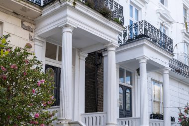 Notting Hill, baharda beyaz evler ve çiçek açan bahçelerle sokaklarda yürümek, şehir hayatı, ilkbaharda Londra, İngiltere 'de varlıklı mahalleler.