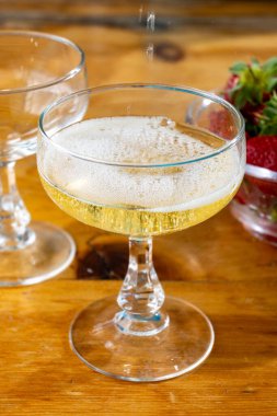 Soğuk brut şampanya köpükleri coupe bardaklarda şarap ve taze çilekli küçük kase.