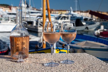 Saint-Tropez 'de eski balıkçı tekneleri limanı ve yat limanında soğuk Fransız gülü Cote de Provence şarabı, Fransa' nın Provence şehrinde yaz tatili