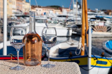 Saint-Tropez 'de eski balıkçı tekneleri limanı ve yat limanında soğuk Fransız gülü Cote de Provence şarabı, Fransa' nın Provence şehrinde yaz tatili