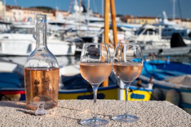 Saint-Tropez 'de eski balıkçı tekneleri limanı ve yat limanında soğuk Fransız gülü Cote de Provence şarabı, Fransa' nın Provence şehrinde yaz tatili