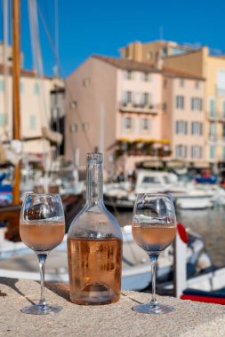 Saint-Tropez 'de eski balıkçı tekneleri limanı ve yat limanında soğuk Fransız gülü Cote de Provence şarabı, Fransa' nın Provence şehrinde yaz tatili
