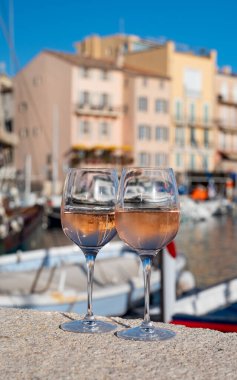 Glasses of cold french rose Cote de Provence wine in old fisherman boats port and yachts harbour in Saint-Tropez, summer vacation on French Riviera in Provence, France clipart