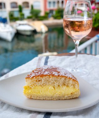 Fransız Riviera şarabı, bir bardak soğuk gül Cote de Provence şarabı ve Port Grimaud 'un yat limanında Tarte Tropezienne keki, Fransa' nın Provence şehrinde yaz tatili