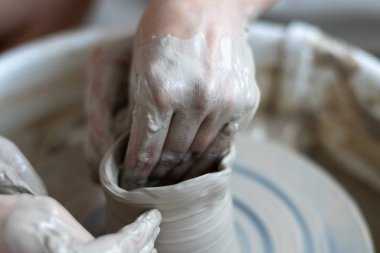 Polonya 'da modern sanat seramik atölyesinde atölye çalışması sırasında çömlekçi çarkında çamur tenceresi yapmak