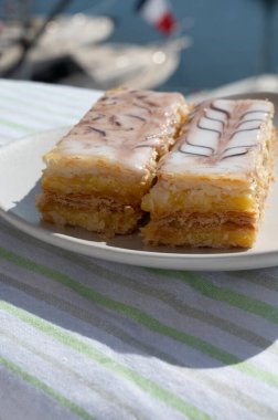 Portion of french mille-feuille cake, vanilla or custard slice, Napoleon puff pastry layered with pastry cream served outdoor in Port Grimaud, France clipart