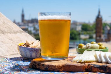 İspanyol birası, peyniri, tapas ve yeşil Endülüs zeytinleri yazın eski Sevilla, Endülüs, İspanya 'nın merkezi manzaralı terasında servis edilir.