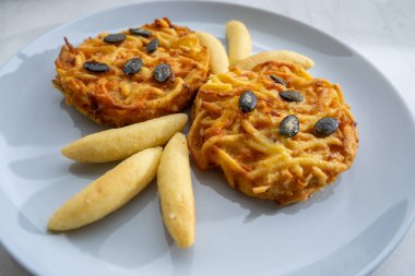 Pumpkin grated roasted patties, rosti or latkes and Fingernudel, finger potato noodle, dumplings decorated with pumpkin seeds close up clipart