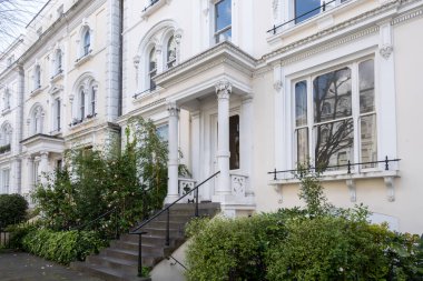 Notting Hill, baharda beyaz evler ve çiçek açan bahçelerle sokaklarda yürümek, şehir hayatı, ilkbaharda Londra, İngiltere 'de varlıklı mahalleler.