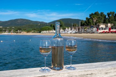 Provence 'den bir şişe soğuk gül şarabı ve beyaz kumlu plaj plajı Plage de Pampelonne, Saint-Tropez yakınlarında, Fransa' da yaz tatili, sahil kulübü partisi.