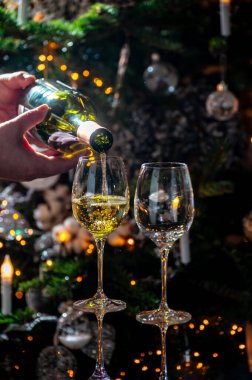 Yeni yıl ya da noel yemeği, bir bardak kuru üzüm ya da arkaplanda Noel ağacı ve çelenk ışıkları olan tatlı tatlı bir tatlı şarap, kutlama konsepti