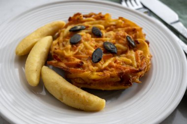 Pumpkin grated roasted patties, rosti or latkes and Fingernudel, finger potato noodle, dumplings decorated with pumpkin seeds close up clipart