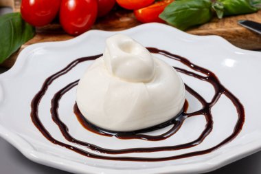 Eating of fresh soft Italian cheese, white balls of burrata or burratina cheese made from mozzarella and cream or gorgonzola filling served with balsamic cream vinegar from Modena clipart